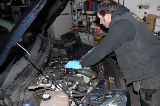 Technician with diagnostic laptop under the bonnet